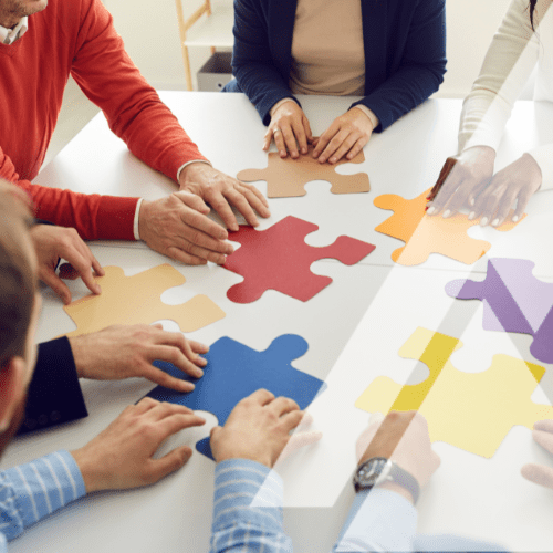 A group of people putting together puzzle pieces.